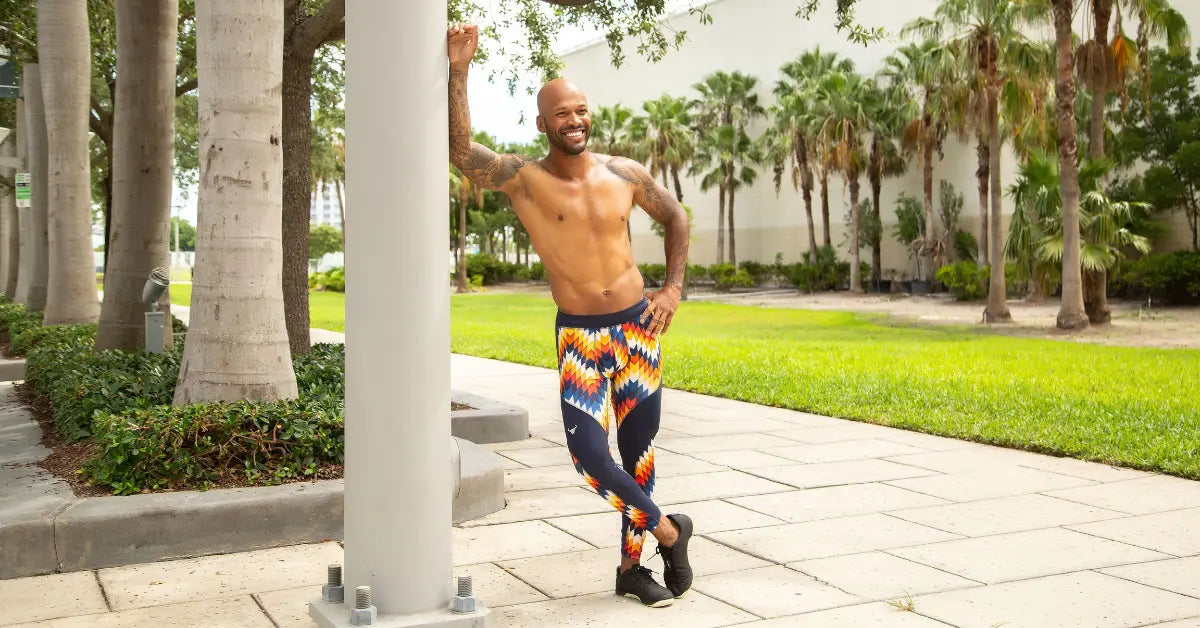 Fitness fashion for men displayed by a confident man in black and white marbled meggings and a matching tank top at a skate park.