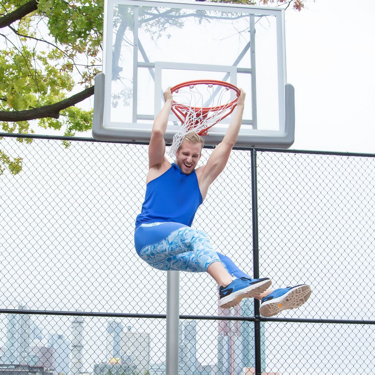 Compression pants for men showcased by a basketball player hanging from a hoop
