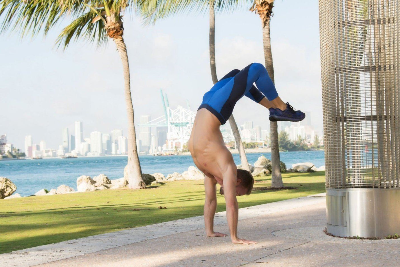 Man performing handstand with river and skyline in background