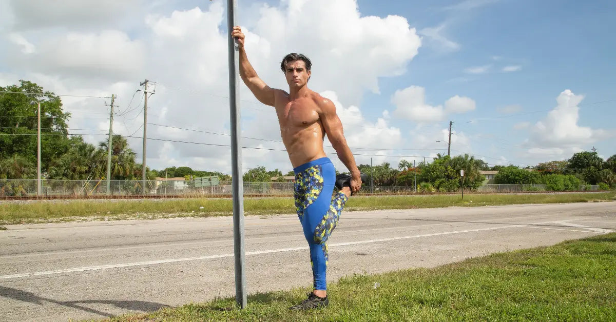 Men's compression wear featuring blue and yellow patterned leggings, worn by a fit man stretching by a roadside pole.