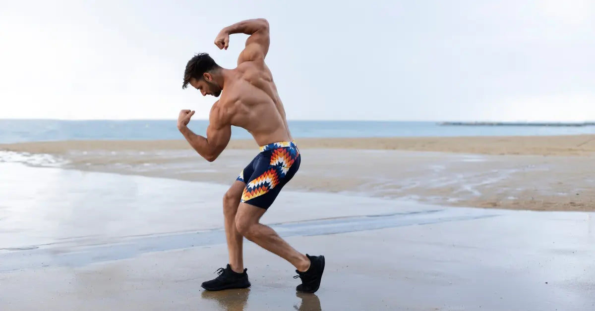 Men’s leggings with a bold geometric pattern worn by a man flexing his muscles at the beach