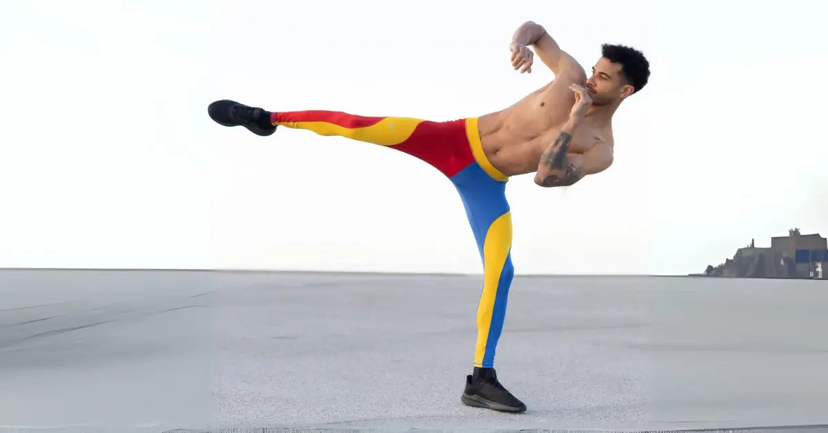 Performance leggings for men in red, yellow, and blue worn by a man performing a high kick outdoors